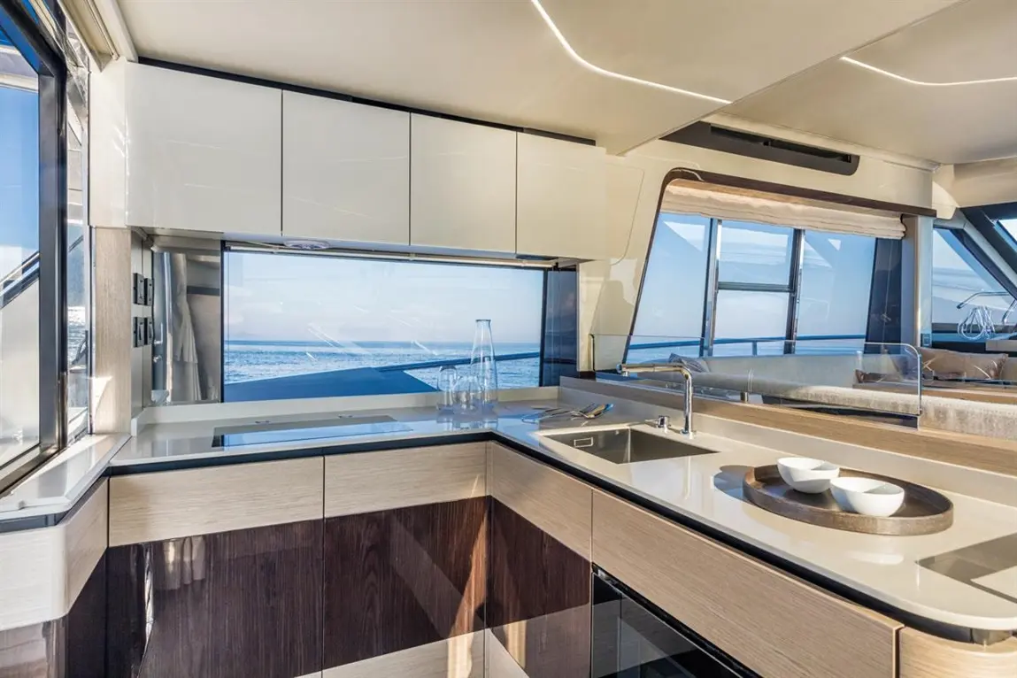 Modern yacht kitchen with a sleek design, large windows showcasing the sea, and minimalist decor including glassware and bowls.